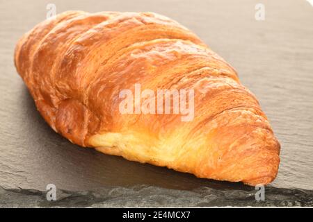 Un fragrante croissant dolce su un'ardesia, primo piano. Foto Stock