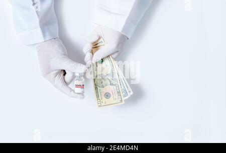 Gli scienziati indossano guanti di gomma che trasportano bottiglie di vaccino COVID-19 e dollari USA isolati su sfondo bianco. Commercio di vaccini per fermare la diffusione del CO Foto Stock