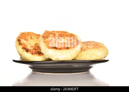 Alcune frittelle di formaggio saporite e cucinate su un piatto di ceramica nera. Lo sfondo è bianco. Foto Stock
