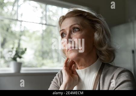Primo piano premuroso infelice donna matura che guarda a distanza Foto Stock