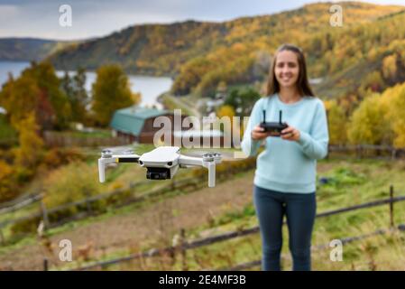 Figura sfocata di ragazza controlla un drone su sfondo sfocato autunno. Confetto messa a fuoco morbida Foto Stock