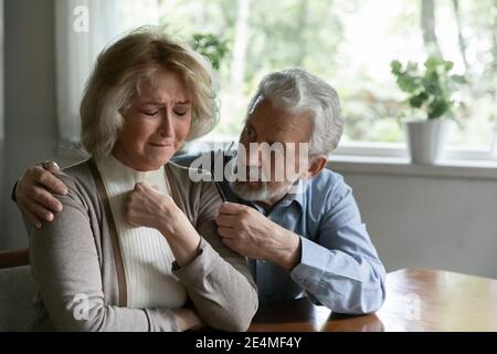 Primo piano uomo maturo confortante frustrata piangendo moglie, abbracciando Foto Stock
