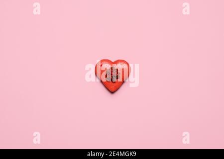 Un macaron di San Valentino a forma di cuore rosso su un pastello sfondo rosa con spazio per la copia e spazio per il testo Foto Stock