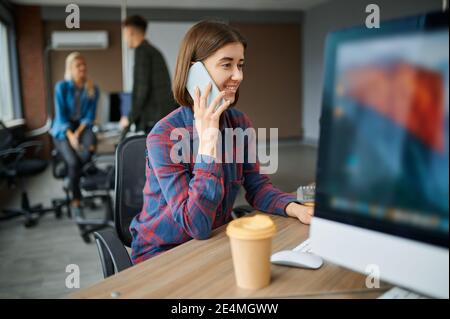 Specialista IT femminile che parla telefonicamente in ufficio Foto Stock