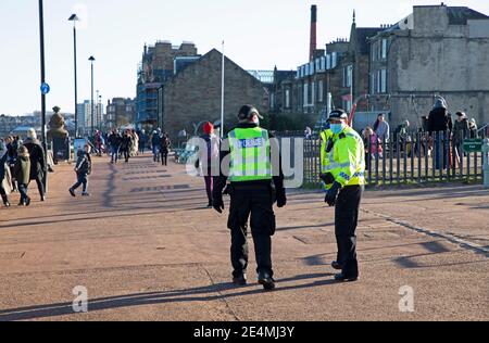 Portobello, Edimburgo, Scozia, Regno Unito. 24 gennaio 2021. Sole pomeridiano e 1 grado centigradi al mare ragionevolmente occupato. Nella foto: Due ufficiali di polizia che fanno un passaggio di routine lungo la passeggiata. Foto Stock