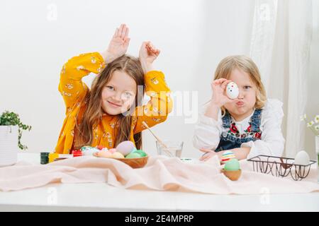 Due bambine sedute dietro un tavolo con uova di pasqua Foto Stock