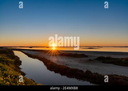 Splendido tramonto sulle paludi e sulle paludi con un cielo colorato e una stella del sole all'orizzonte Foto Stock