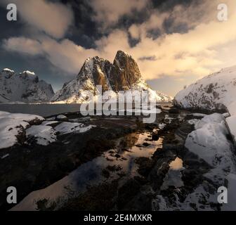 EPIC Hannoy picchi durante un freddo alba invernale, riflessa in piscine ghiacciate, Lofoten, Norvegia Foto Stock