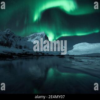 Aurora boreale luminosa su montagne epiche frastagliate e innevate, Lofoten, Norvegia Foto Stock