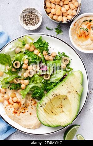 Ciotola per insalata con avocado, hummus e green. Insalata vegetariana vegana sana. Vista dall'alto Foto Stock