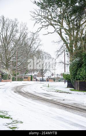 I cingoli degli pneumatici conducono intorno ad una curva su una strada innevata a Reading, Berkshire, Regno Unito Foto Stock