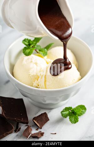 Versare la salsa al cioccolato sul gelato Foto Stock