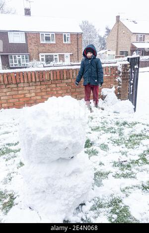 Bambini che costruiscono un pupazzo di neve in un giardino anteriore a Reading, Regno Unito dopo la prima nevicata dell'inverno. Foto Stock