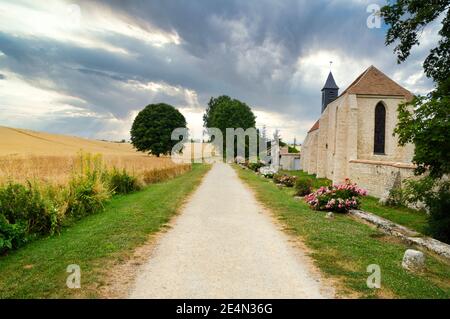 Bellissimo paesaggio di campagna, con un campo di grano e una chiesa, sotto un cielo tempestoso. Foto Stock