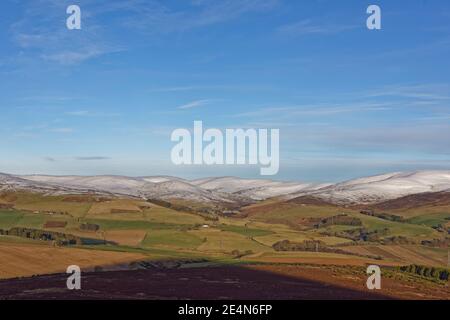 Il sole che si inneve sulle Glene Angus guardando verso Glen Esk, con neve sulle cime delle colline sopra le Farms sulle pendici inferiori. Foto Stock