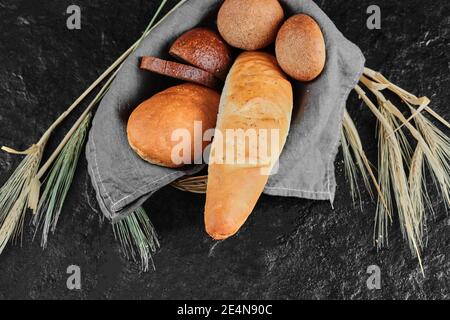 Vista ad alto angolo di una varietà di pane fatto in casa in legno cestino con tovaglia Foto Stock