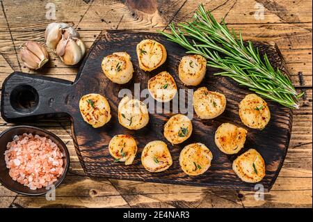 Barbecue capesante scottate con salsa al burro su tavola di legno. Sfondo di legno. Vista dall'alto Foto Stock
