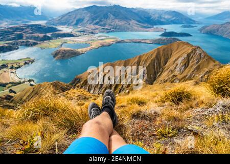 Avventura e trekking wanderlust viaggio concetto di vacanza con escursionisti scarpe da trekking primo piano. Uomo escursionista che guarda la vista dalla famosa escursione a Roys Peak ON Foto Stock