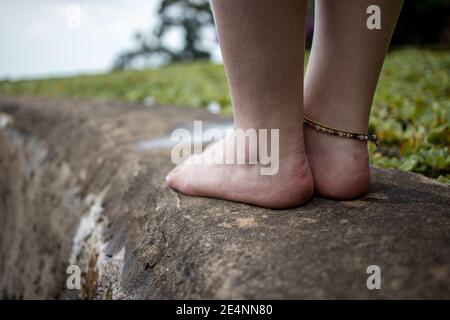 le gambe femminili con un braccialetto sul lato del stagno sullo sfondo di un paesaggio naturale Foto Stock