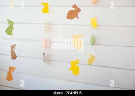 Decorazioni di pasqua. Ghirlanda con uova e del viola e il colore bianco, ghirlanda con conigli contro lo sfondo di una parete di legno scuro. Foto Stock