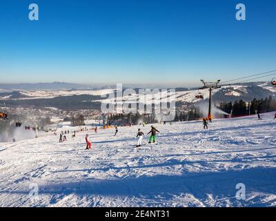 Piste da sci, seggiovie, sciatori e snowboarder nella località sciistica di Bialka Tatrzanska in Polonia in inverno. Cannoni da neve in azione Foto Stock