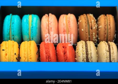 Mucchio di macaron colorati e dolci in scatola regalo blu, dessert francese delizioso, piatto, vista dall'alto. Foto Stock