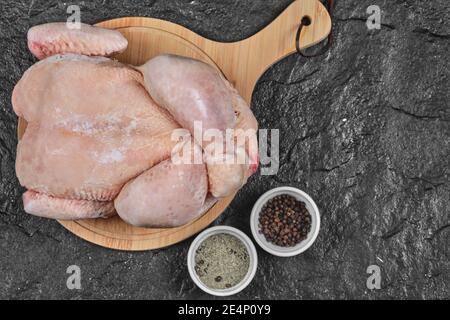 Pollo intero crudo su tavola di legno con spezie Foto Stock