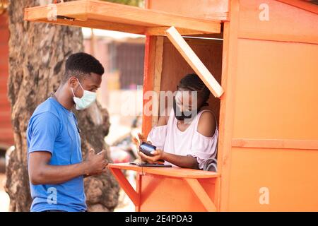giovane nigeriano che utilizza un servizio di pos per prelevare contanti Foto Stock