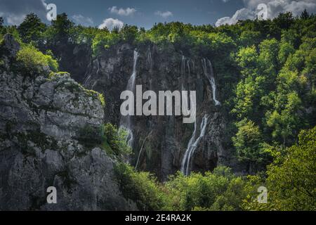 Parzialmente nascosto dalla scogliera e dalla foresta, Veliki Slap, la cascata più alta dei laghi di Plitvice, Parco Nazionale Patrimonio Mondiale dell'UNESCO, Croazia Foto Stock