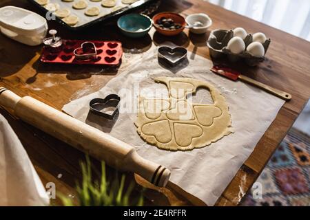 Pasta cruda, biscotti muffe, oklova, molti ingredienti per torte e muffe a cuore sulla tavola. Foto Stock