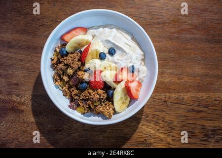 Ciotola di muesli con frutta fresca e yogurt sul tavolo al caffè. Foto Stock