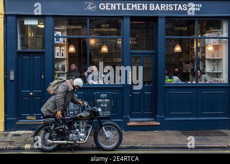 Un uomo arriva in un bar a Londra con moto classica. Foto Stock