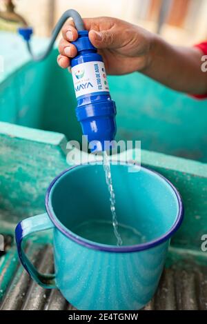 Una donna utilizza un sistema di filtrazione dell'acqua pulita basato sul rubinetto a casa sua a Cantel, Guatemala. Foto Stock