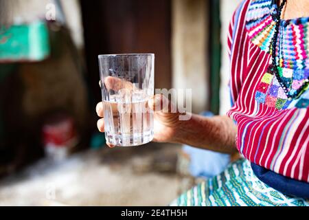 Una donna anziana beve un bicchiere d'acqua pulita a San Juan la Laguna, Guatemala, America Centrale. Foto Stock