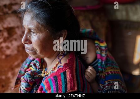 Ritratto di una donna anziana che porta un bambino a casa sua a Cantel, Guatemala, America Centrale. Foto Stock