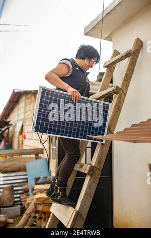 Un tecnico della società locale di energia senza scopo di lucro installa un nuovo sistema di illuminazione a energia solare in una casa a Cantel, Guatemala. Foto Stock