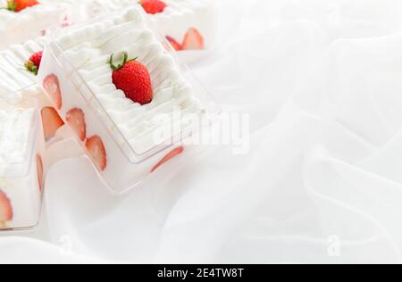 Shortcake di fragole in scatola di plastica su con fondo di stoffa e spazio di copia, il concetto minimo di torta e panificio Foto Stock