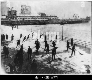 Gli uomini la rimozione di neve off boardwalk, Atlantic City, N.J., La Domenica di Pasqua; siepi Pier in backgrd. Foto Stock