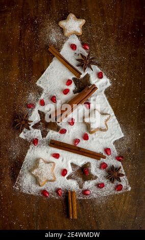 Biscotti fatti in casa piegati sotto forma di un albero di Natale con cannella su una teglia da forno con zucchero in polvere, vista dall'alto Foto Stock