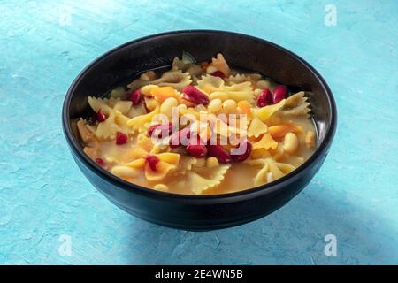 Zuppa vegana con verdure, pasta e fagioli, su fondo blu Foto Stock