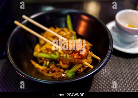 Cibo tailandese-Stir fritto Noodle, Pad Thai in piatto scuro con bastoni. Foto Stock