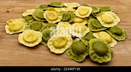 Ravioli italiani non cotti con burro, ricotta e basilico su tavola di legno Foto Stock