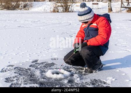 Boy ama la pesca invernale sul ghiaccio del lago Foto Stock