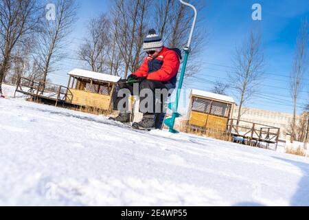 Boy ama la pesca invernale sul ghiaccio del lago 28 Foto Stock