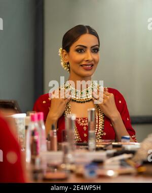 Indian Bride durante la sessione di trucco guardando in speculare Foto Stock