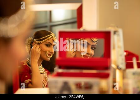 Sposa indiana durante la sessione di trucco Foto Stock