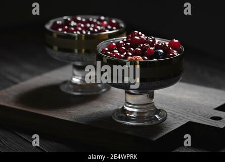 primo piano di una colazione deliziosa e sana. foto a fuoco selettivo di semi di chia, yogurt naturale e frutti di bosco freschi come mirtilli rossi e fragole Foto Stock