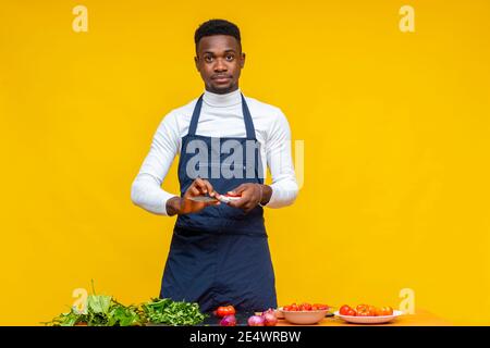 ritratto di uno chef che tiene un coltello e ne ha alcuni ingredienti davanti a lui per preparare un piatto Foto Stock