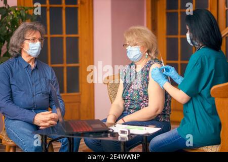 Persone anziane con maschere facciali vaccinate da un infermiere contro virus covid-19 Foto Stock