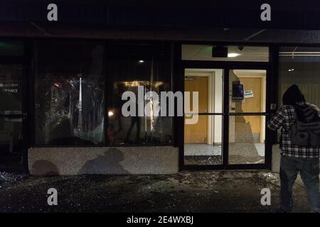 Tacoma, Stati Uniti. 24 gennaio 2021. In tarda serata, le finestre dell'edificio Sound 911 sono danneggiate durante la protesta della polizia di Aabolire Tacoma. La protesta si è formata dopo che un video è stato condiviso e ampiamente diffuso sui social media la sera precedente. Il video condiviso mostra un ufficiale della polizia di Tacoma che guida un SUV attraverso una folla di pedoni e successivamente guida sopra una persona. Una folla numerosa era un raduno che guardava un sideshow di strada. Due persone sono state successivamente portati al pronto soccorso, una rimane ancora con gravi lesioni. Credit: James Anderson/Alamy Live News Foto Stock